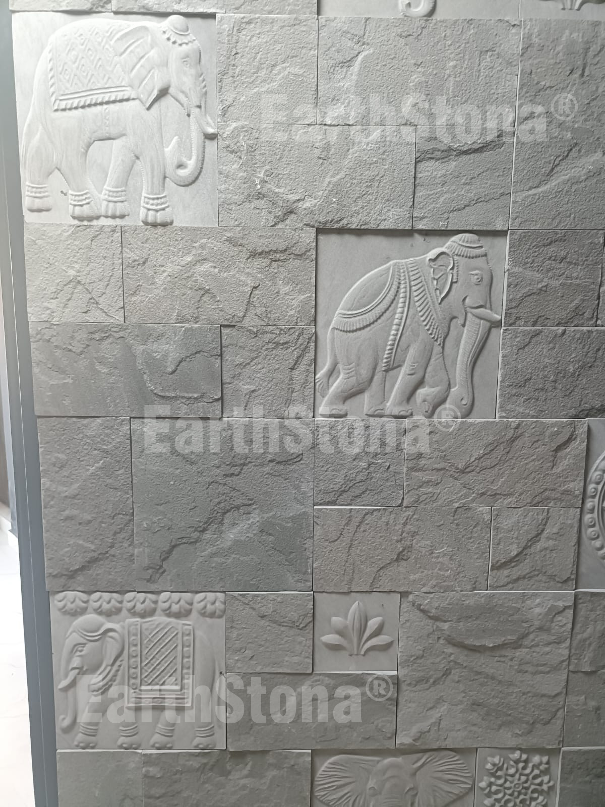 Hand carved elephant motif natural stone wall cladding panel installed on luxury bungalow entrance foyer wall